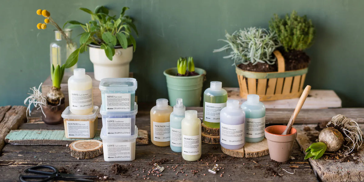 Davines hårplejeprodukter fra serierne LOVE, MOMO, MINU og NOUNOU på et rustikt bord med planter.